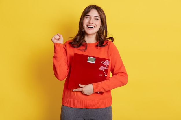 happy woman holding a weighing scale