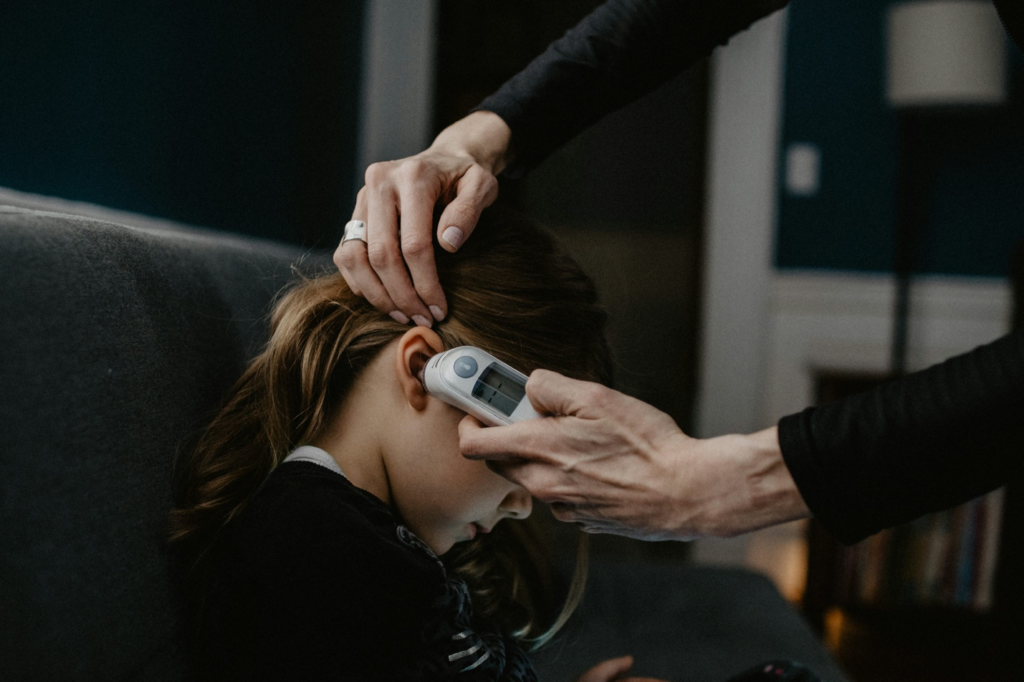 A mother using a thermometer to check her child's temperature.