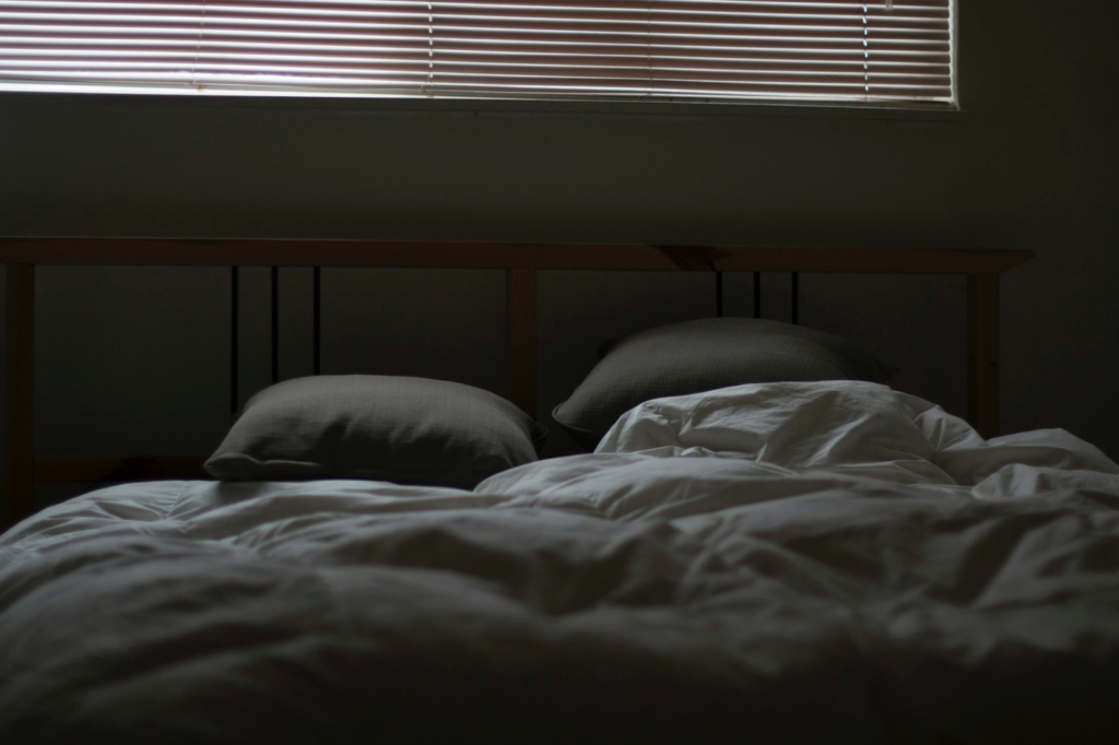 A bed with messy sheets and pillows, suggesting a restless night's sleep.