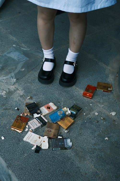 Person standing near discarded cigarette packs, symbolizing quitting smoking.